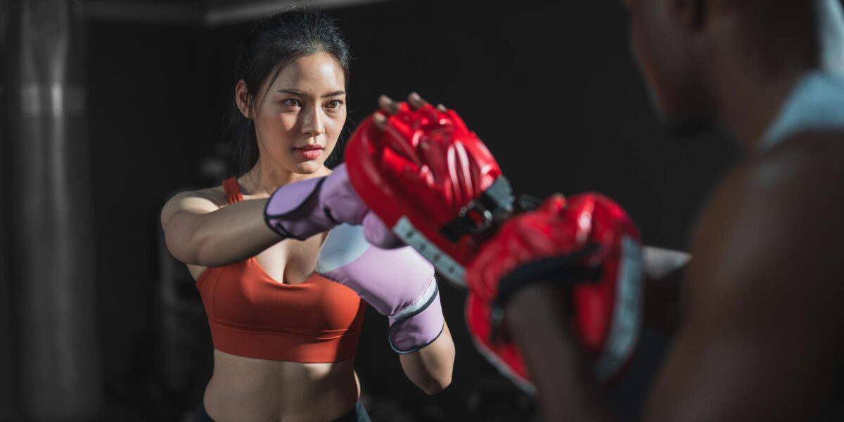 asian female wearing boxing gloves with her trainer training exercise boxing gym ()