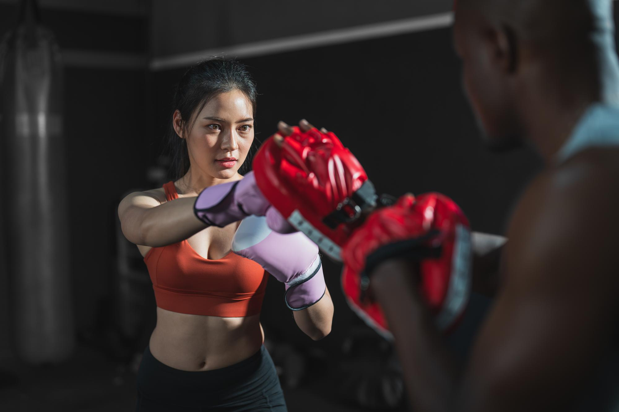 Confident girl training boxe in a open public gym, dramatic light